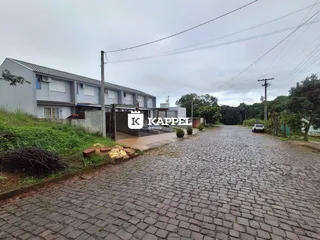 Fachada de um prédio residencial em Lajeado, Brasil, com uma rua pavimentada de paralelepípedos.