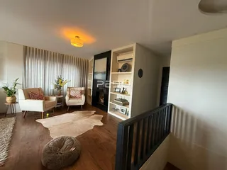 Sala de estar com piso de madeira e estantes em um apartamento.