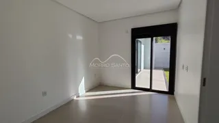 Hall de entrada com paredes brancas e piso claro, com porta de vidro para o exterior.