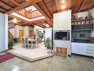 Interior de uma sala de estar com pé direito alto e decoração rústica.