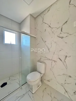 Foto de um banheiro com revestimento em mármore branco e box de vidro.