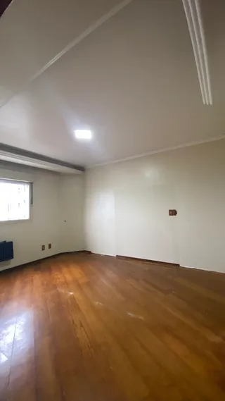 A sala apresenta piso de madeira e paredes brancas.
