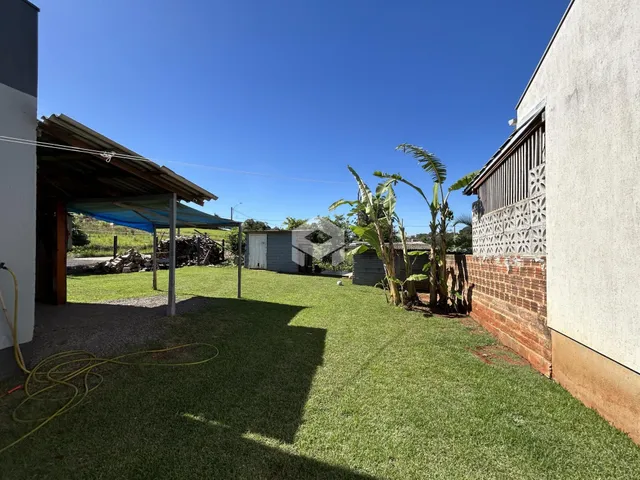 Vista externa de uma propriedade com gramado e muro de tijolos.