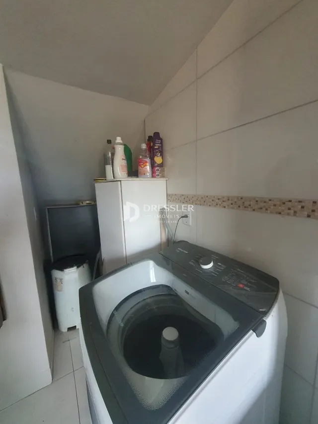 Vista interna de um corredor com paredes brancas e azulejos.