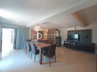 Sala de jantar ampla com mesa de madeira e cadeiras em um apartamento.