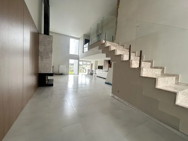 Corredor interno de uma casa moderna com piso de cerâmica e escadaria.