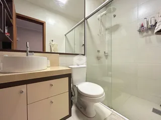 Foto de um banheiro moderno com box de vidro e louças brancas.
