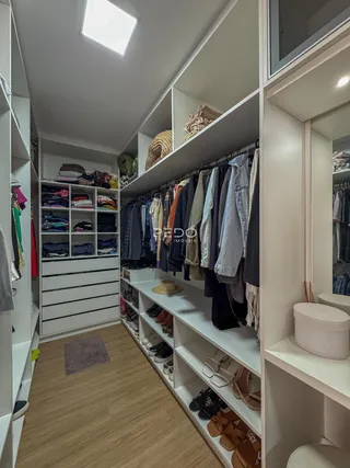 Quarto com estantes brancas e organização de roupas.