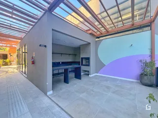 Vista de uma área externa coberta com estrutura de vidro e parede colorida.