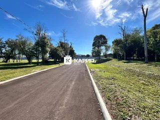 Uma estrada de terra leva a uma área gramada sob um céu azul.