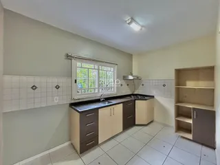 Vista interna de uma cozinha com armários e piso cerâmico.