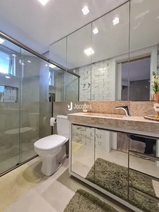Foto de um banheiro com revestimento de azulejo e divisória de vidro.