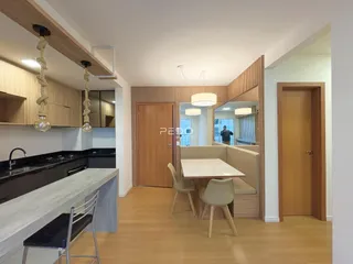 Interior de uma sala de jantar com piso de madeira e cozinha moderna.