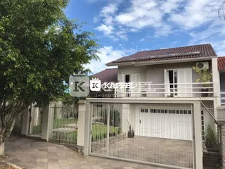 Fachada da residência com portão de ferro e área externa gramada.