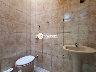 Foto de um banheiro com revestimento de azulejos claros e louças brancas.