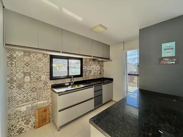 Cozinha com armários brancos e revestimento de azulejos no fundo da parede.
