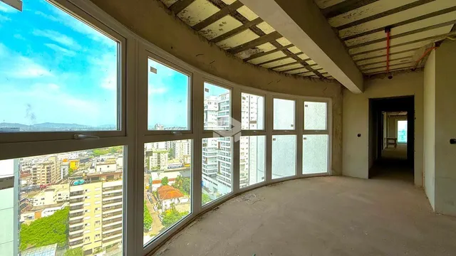 Vista da sala com grandes janelas que mostram a paisagem urbana.