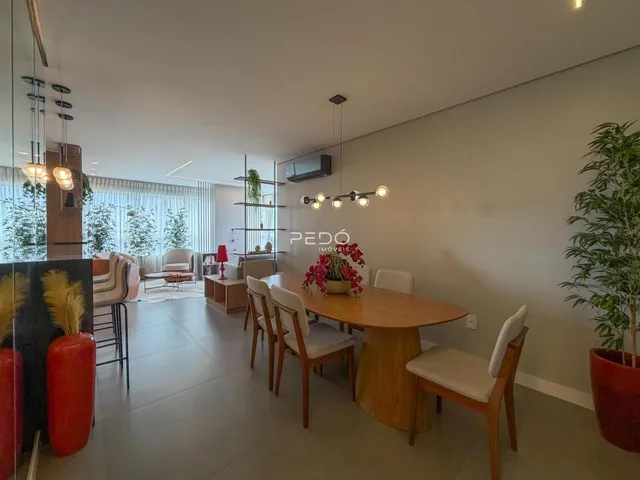 Sala de estar e jantar com piso de madeira clara e grandes janelas.