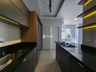 Vista da cozinha moderna com armários escuros e bancadas claras.