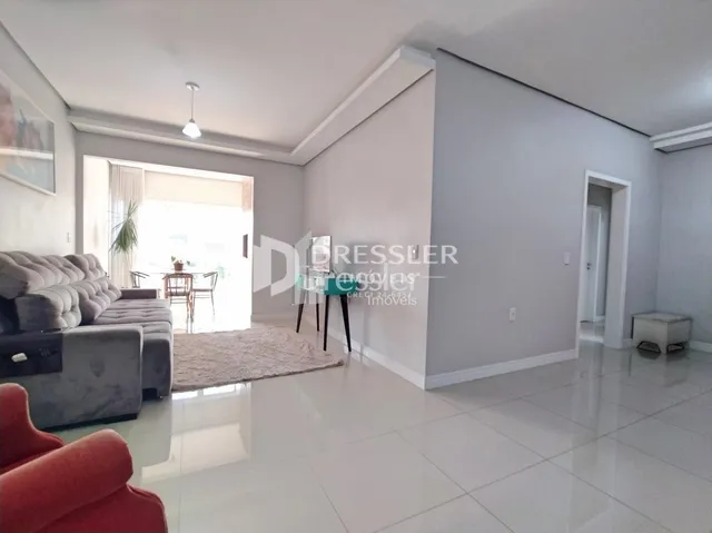 Sala de estar clara com paredes brancas e piso claro.