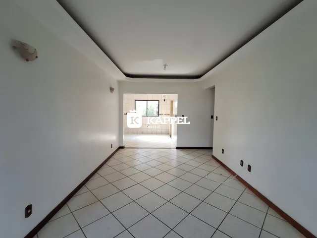 Foto de um corredor interno com piso de cerâmica clara e paredes brancas.