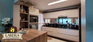 Vista interna de uma cozinha com armários e bancadas de madeira.
