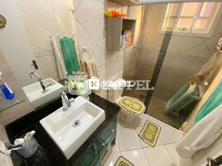 Foto de um banheiro com pia branca e revestimento de azulejos claros.