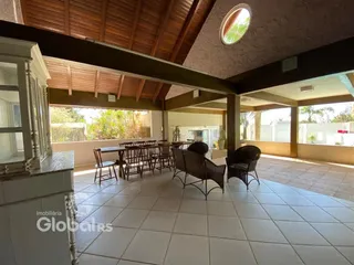 Área de jantar coberta com piso de cerâmica e estrutura de madeira.