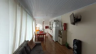 Sala de estar com piso de madeira e cortinas brancas.
