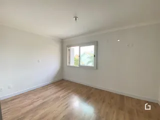 Ambiente interno de uma sala com piso de madeira clara e janela.