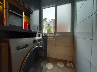 Foto de uma área interna com máquina de lavar e janela de vidro.