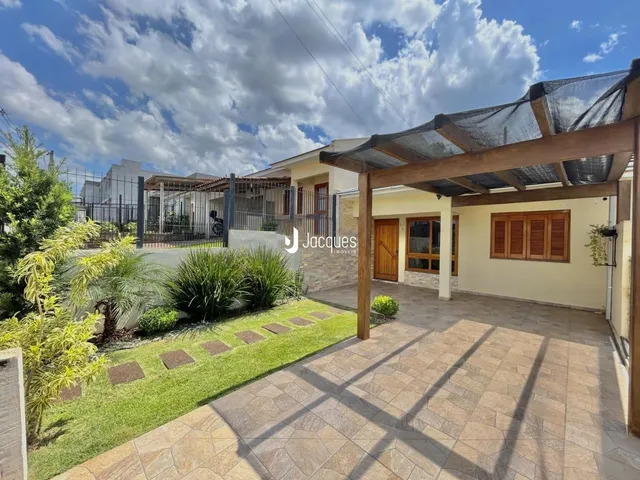 Fachada de uma residência com área externa gramada e cobertura.