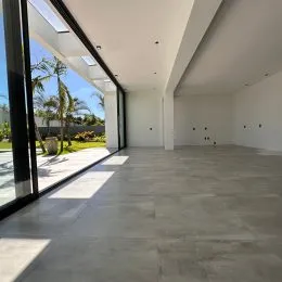 Ambiente interno amplo com piso de concreto e grandes portas de vidro que dão vista para o exterior.