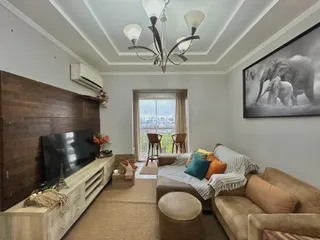 Sala de estar com sofá e televisão em um apartamento.