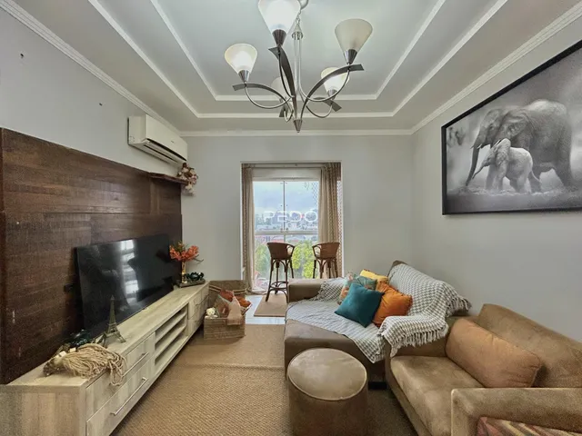 Sala de estar com sofá e televisão em um apartamento.