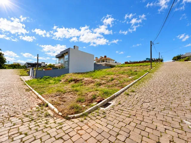 Fachada de uma casa moderna em Lajeado, Brasil, com terreno gramado e estrada de paralelepípedos.