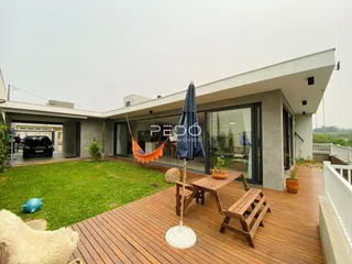 Vista da área externa de uma residência com deck de madeira e gramado verde.