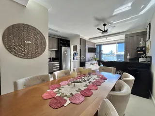 Sala de jantar com mesa de madeira e ambiente moderno em apartamento.