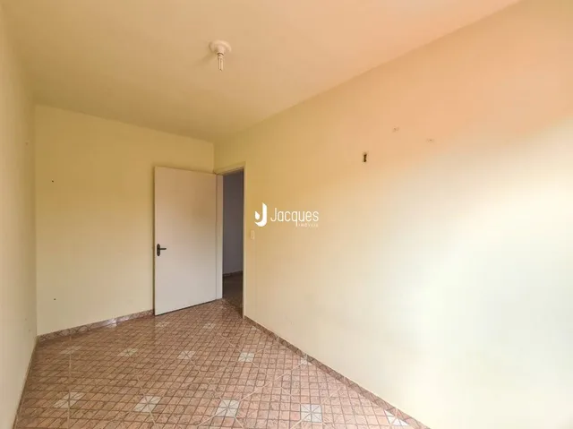 Vista interna de um corredor com paredes claras e piso de cerâmica.