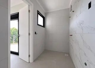 Hall de entrada com paredes brancas e piso claro.