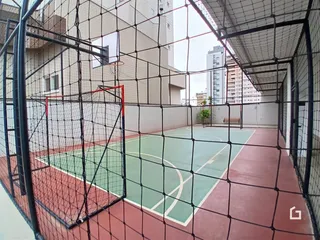 Imagem de uma quadra esportiva externa cercada por tela de arame.