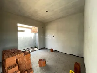 Interior de um cômodo com paredes de reboco e piso de concreto em construção.