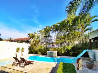 Piscina externa com escorrega em área verde.