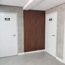 Hall de entrada com painel de madeira escura e portas brancas.