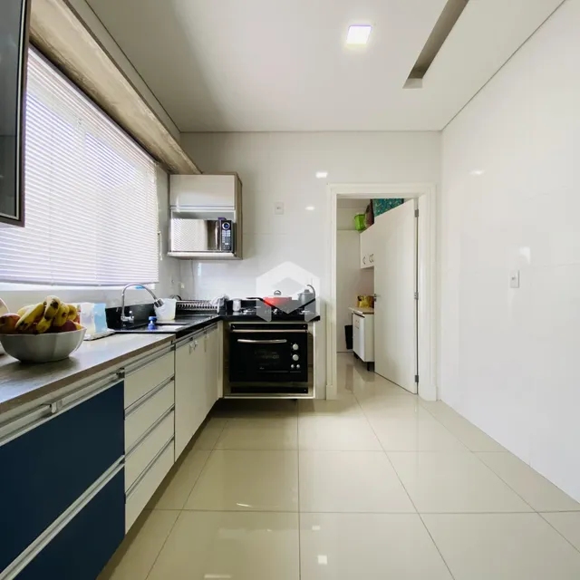 Vista da cozinha com armários brancos e piso claro.
