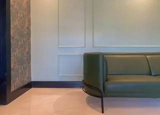Foto de uma sala de estar com um sofá verde e parede decorada.