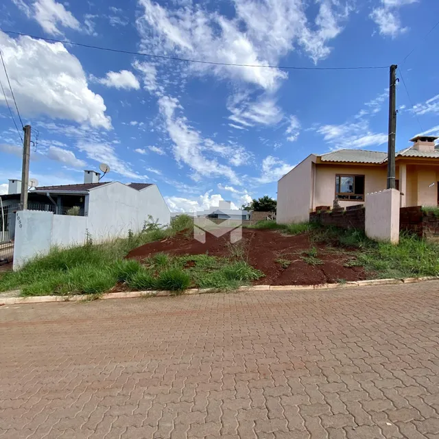 Vista externa de uma propriedade com terreno gramado e rua pavimentada.