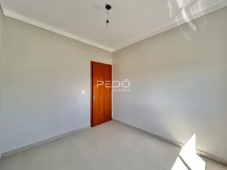 Interior de uma sala com paredes brancas e piso claro.