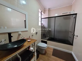 Foto de um banheiro com box de vidro e bancada de madeira.