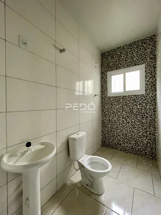 Foto de um banheiro com azulejos brancos e louças sanitárias.
